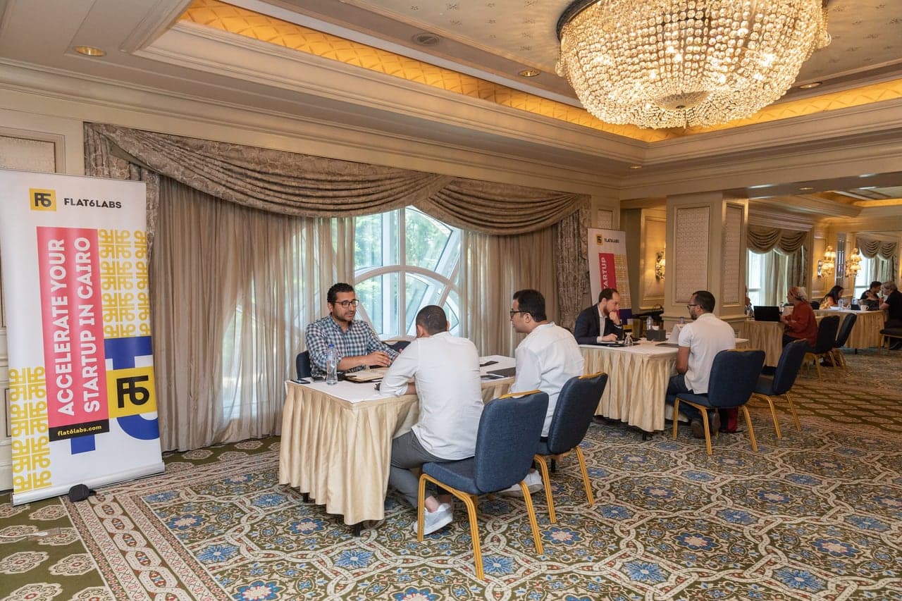 One-to-one meetings between investors and founders under the ballroom chandeliers.
