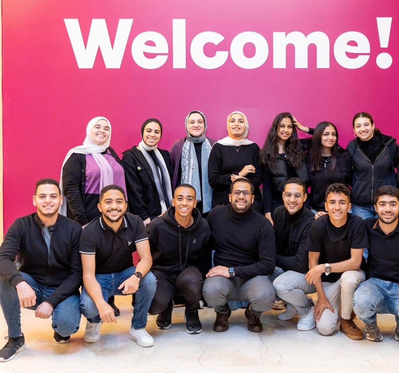 Breadfast's team gathered under the pink "Welcome!" wall at their employee gathering.