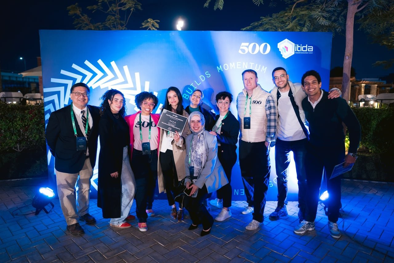 Founders celebrating in front of the backdrop under blue uplights.