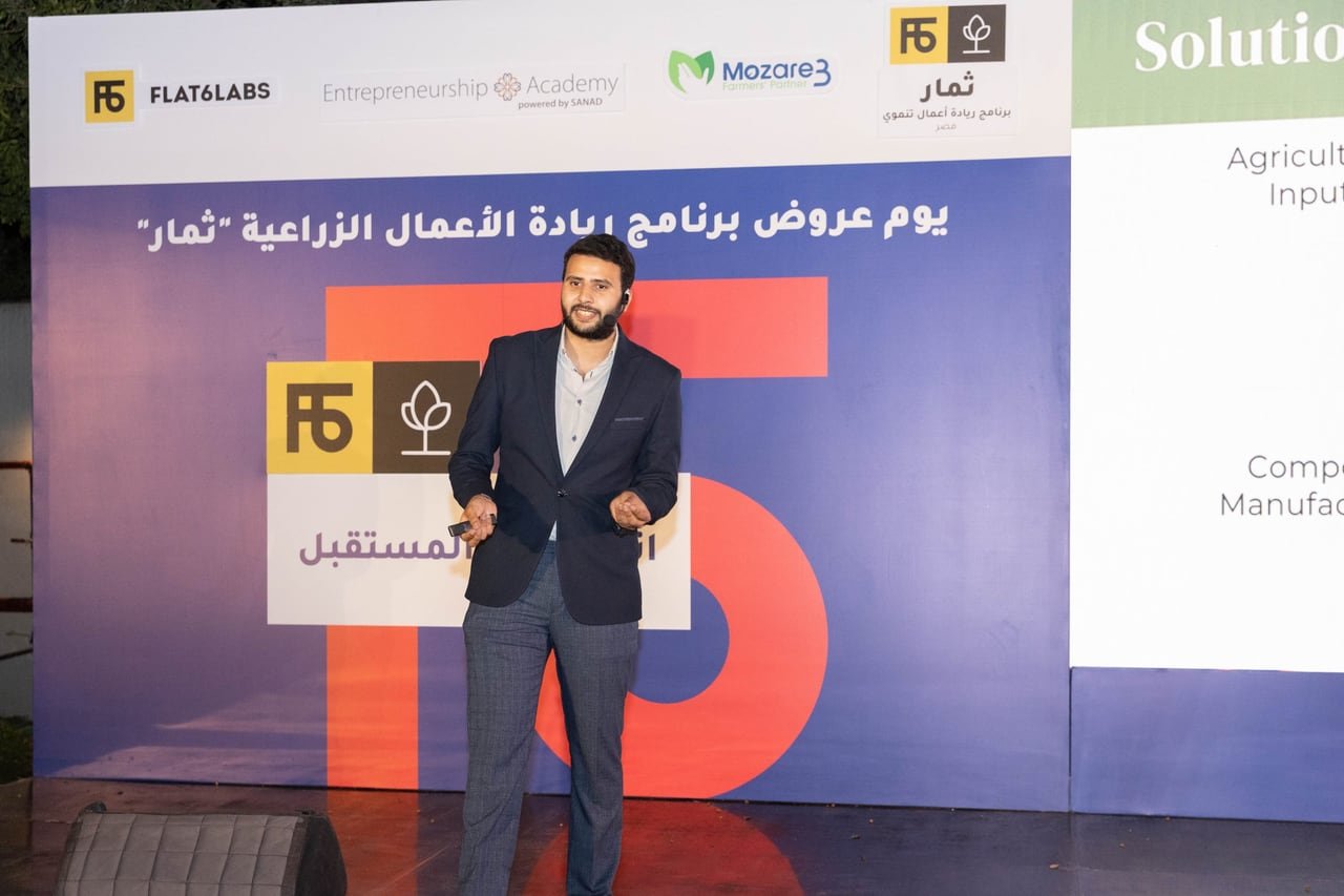 A founder on stage with his solution slide behind him.
