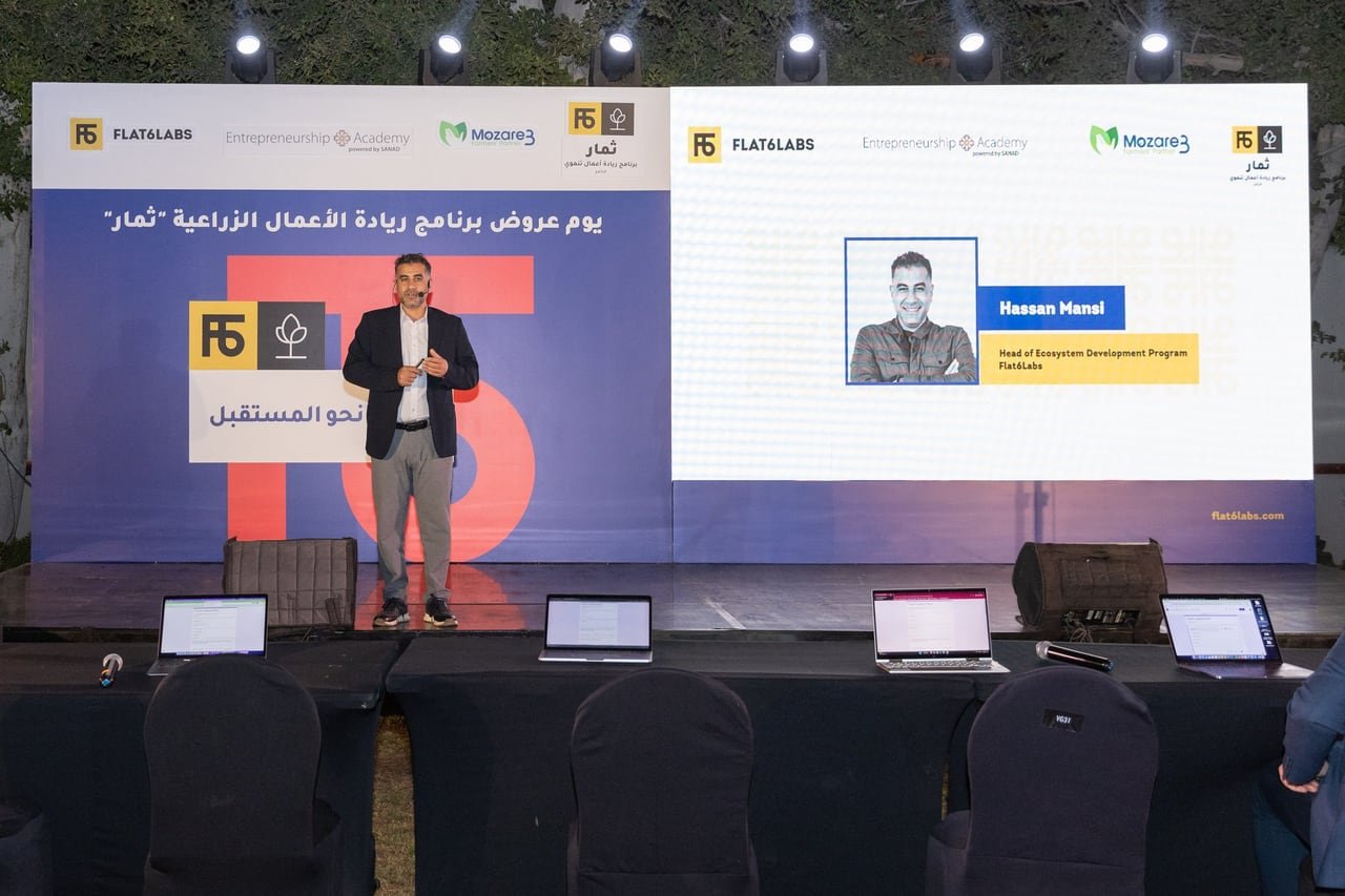 A founder pitching on stage in front of the Thimar demo day screen.