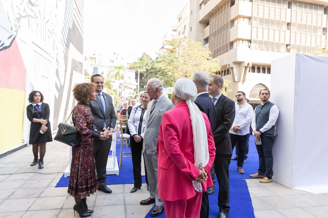 The delegation passing the mural along the blue carpet.