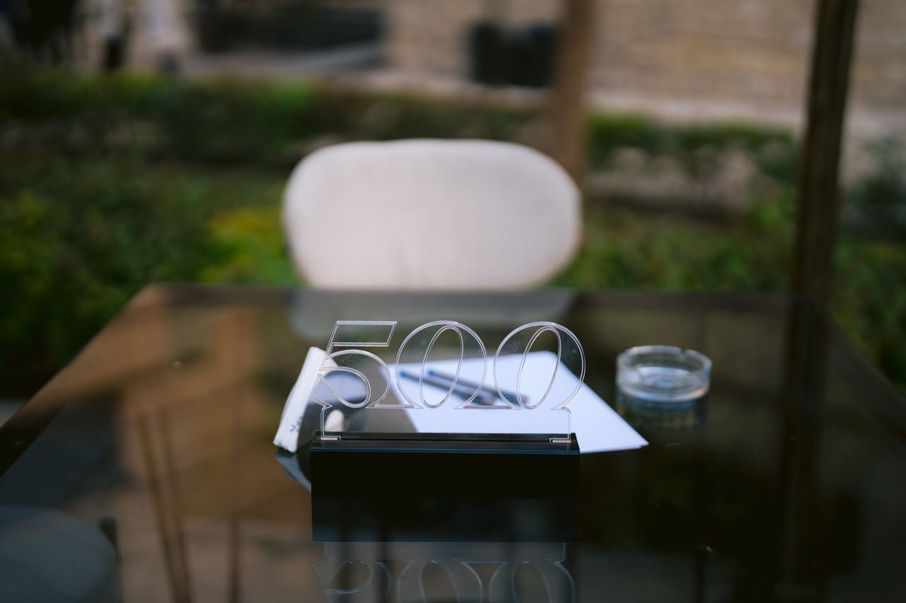 A table dressed with the 500 acrylic logo, notepads and pens.