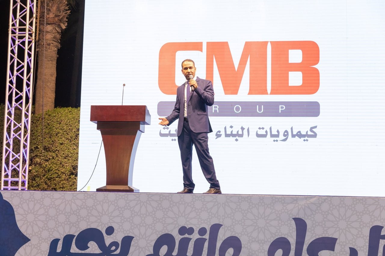 A speaker on stage in front of the CMB Group logo.