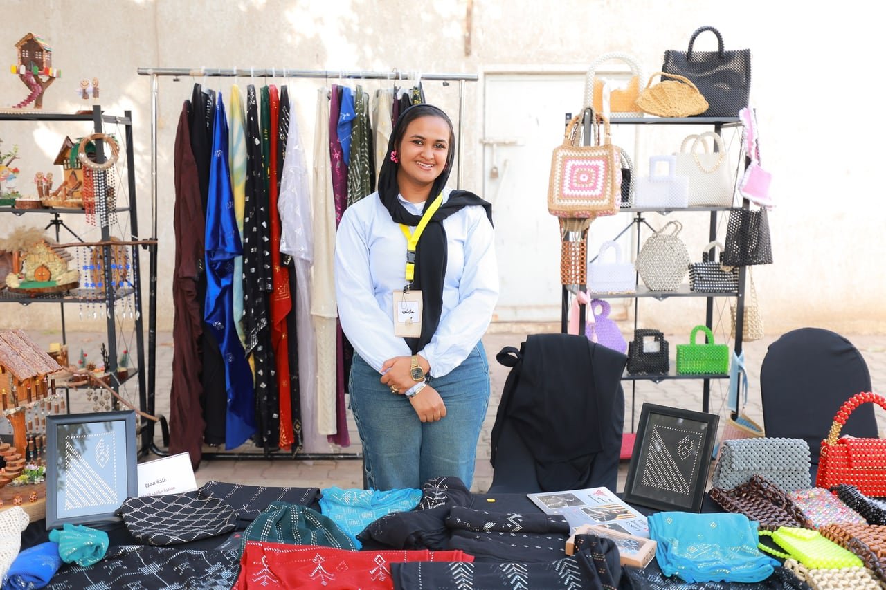 An exhibitor standing at her clothing and handbag stall.