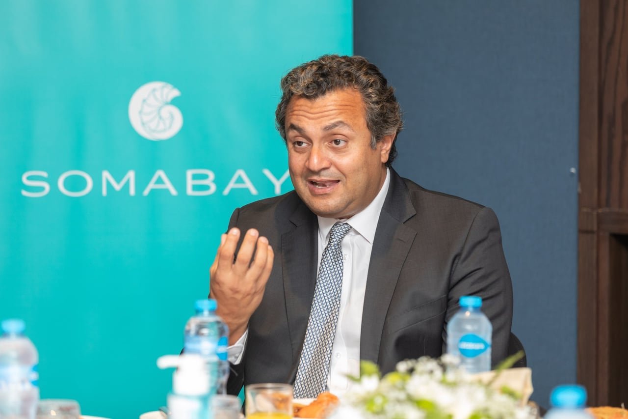 A speaker in front of the Somabay banner.