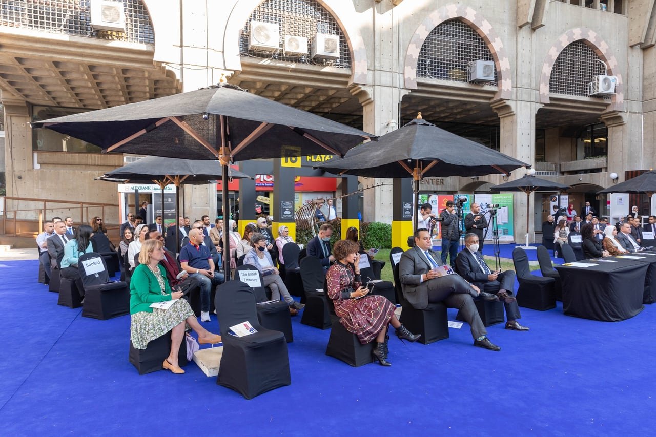 The audience under black umbrellas in the courtyard during the forum.
