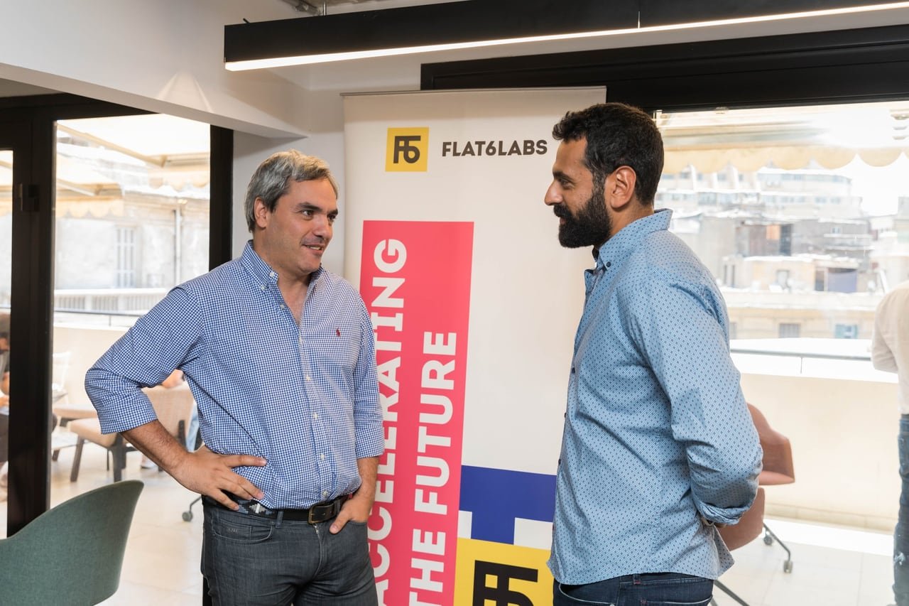 حوار بين جلستين بجوار لافتة Flat6Labs.