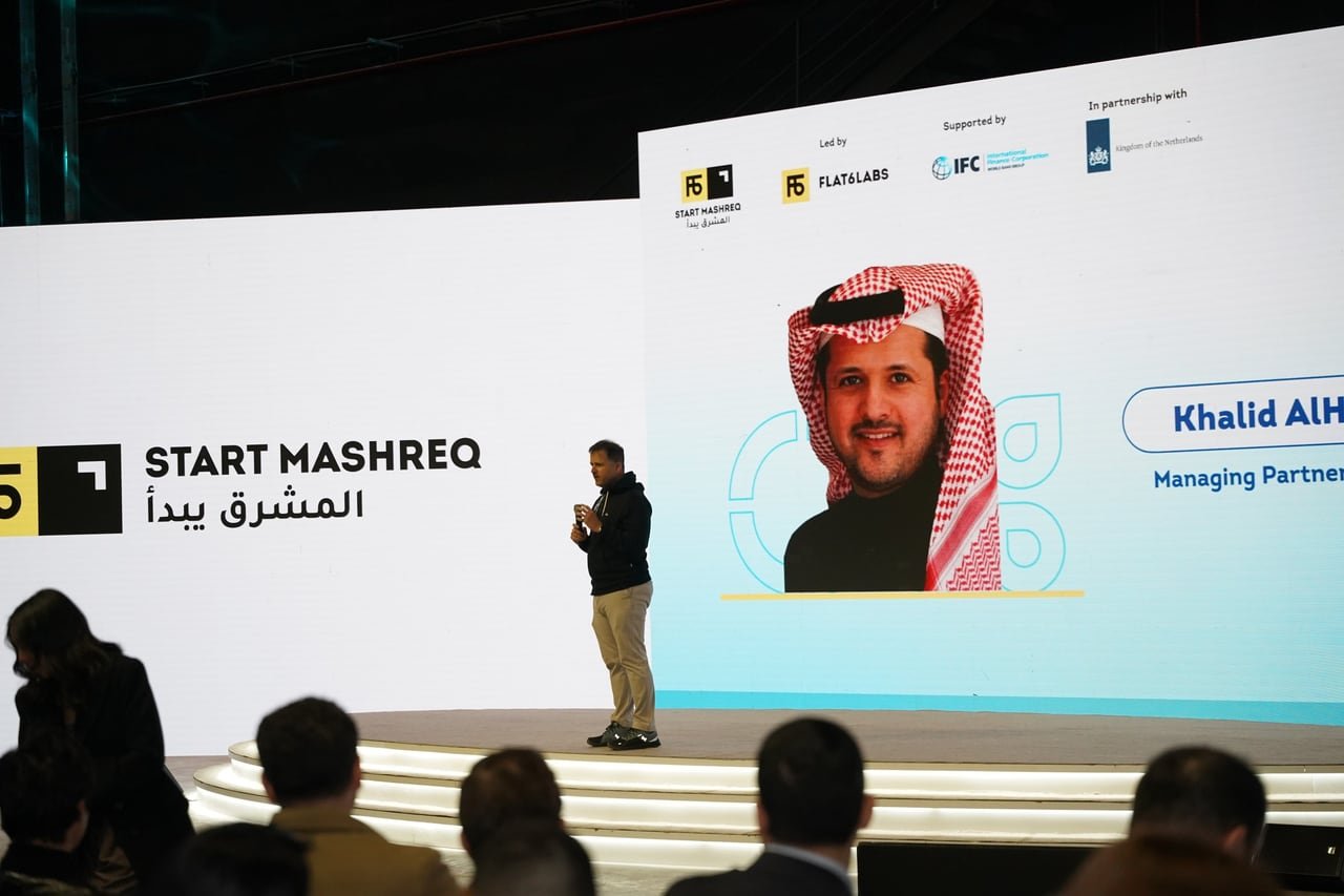 A speaker on stage in front of the StartMashreq screens.