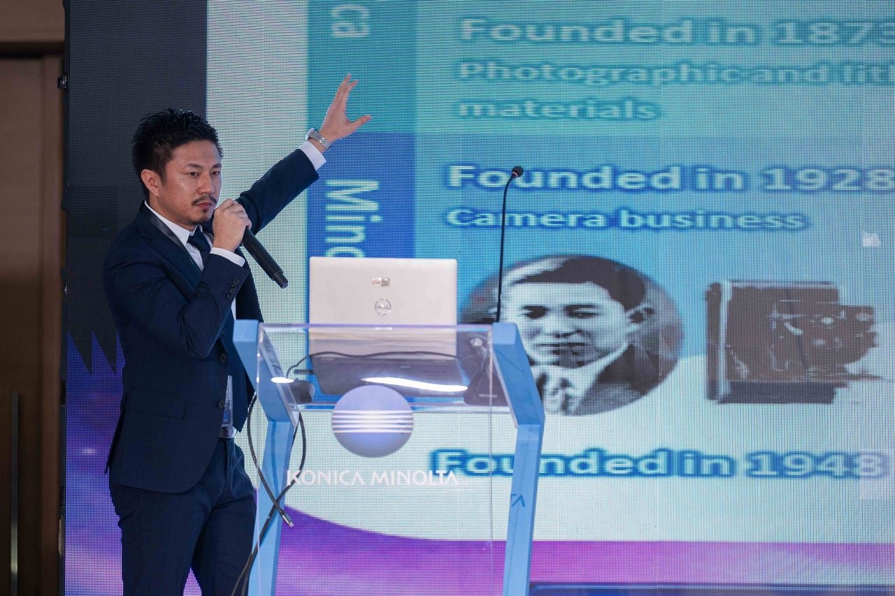 A Konica Minolta speaker presenting the company's history.