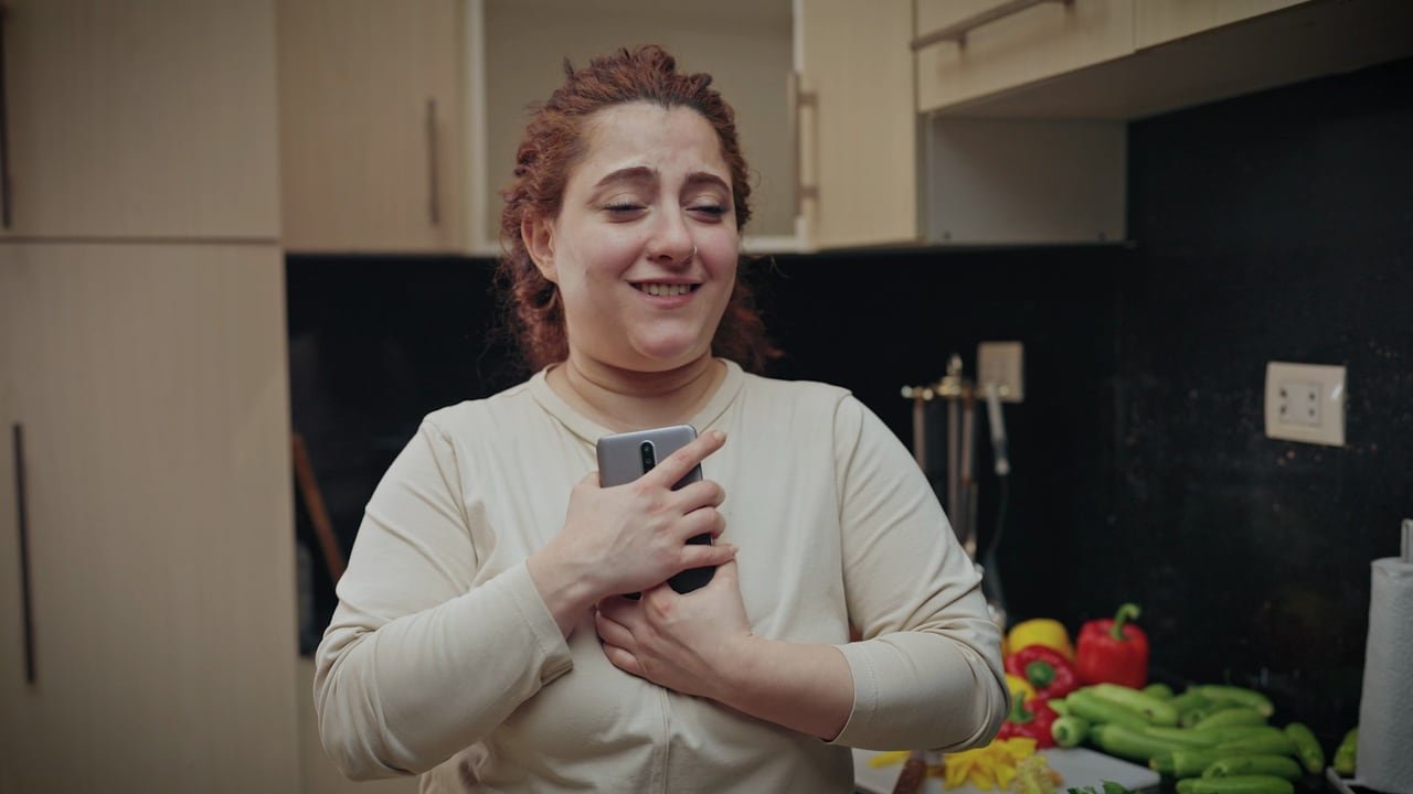 امرأة تبتسم وهاتفها على صدرها.