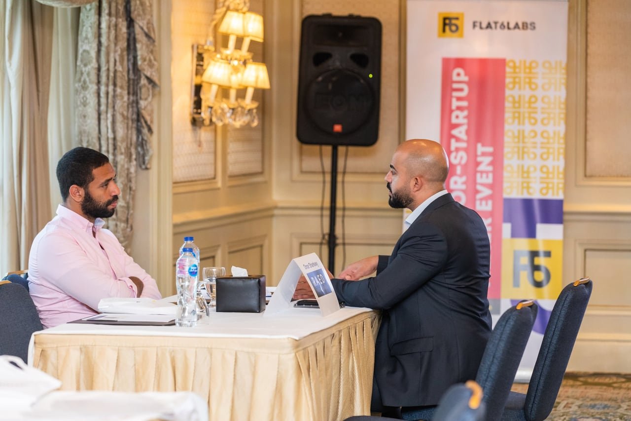 لقاء فردي أمام لافتة Investor–Startup Mixer.