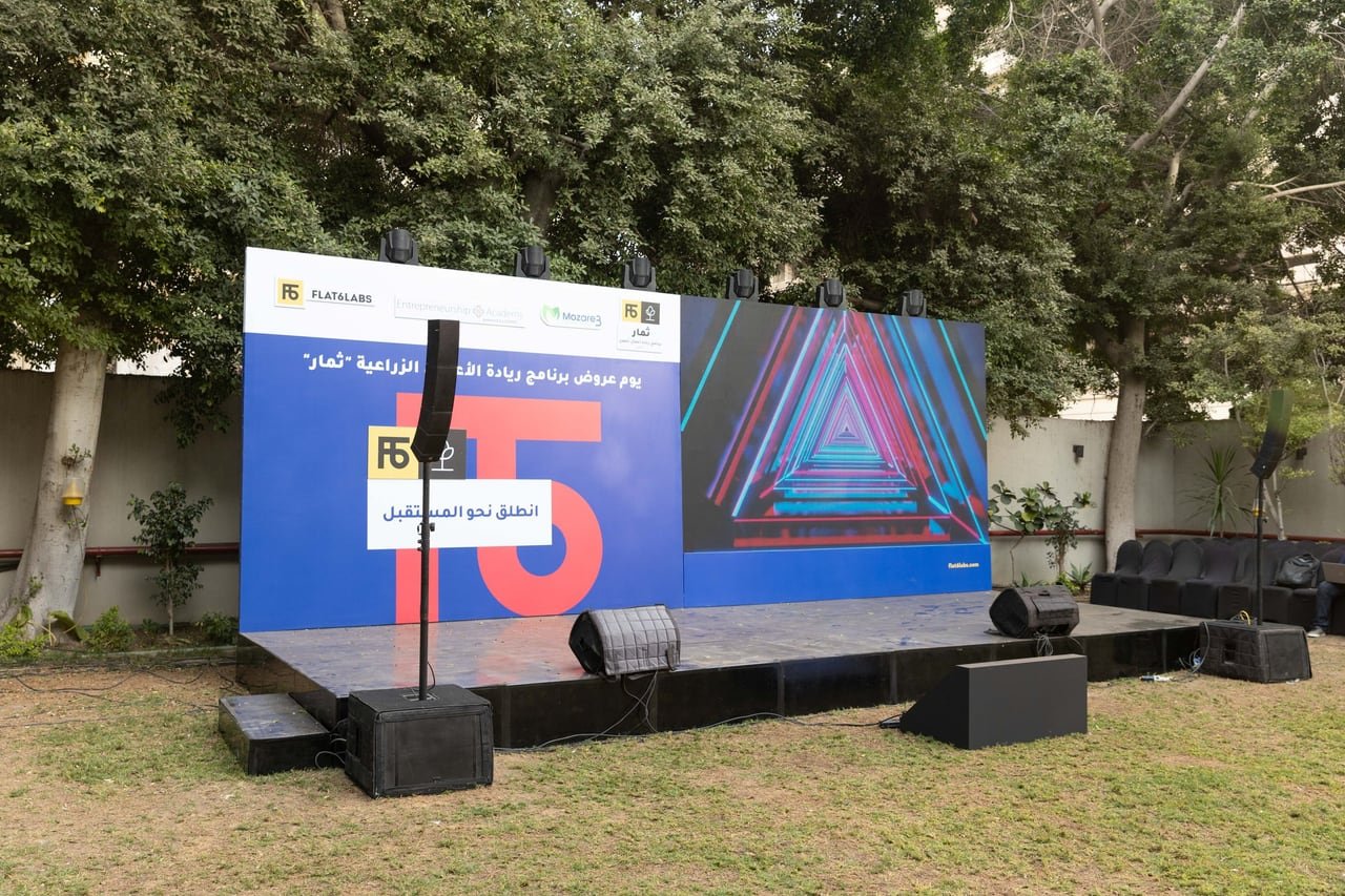 The stage, its screen and speakers ready in the garden in daylight.