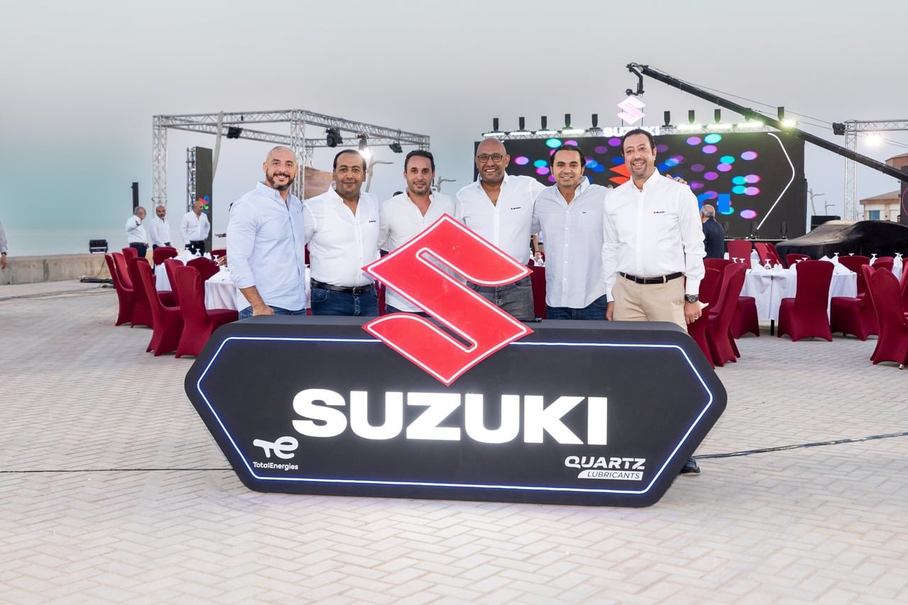 Suzuki's team behind the illuminated Suzuki sign.