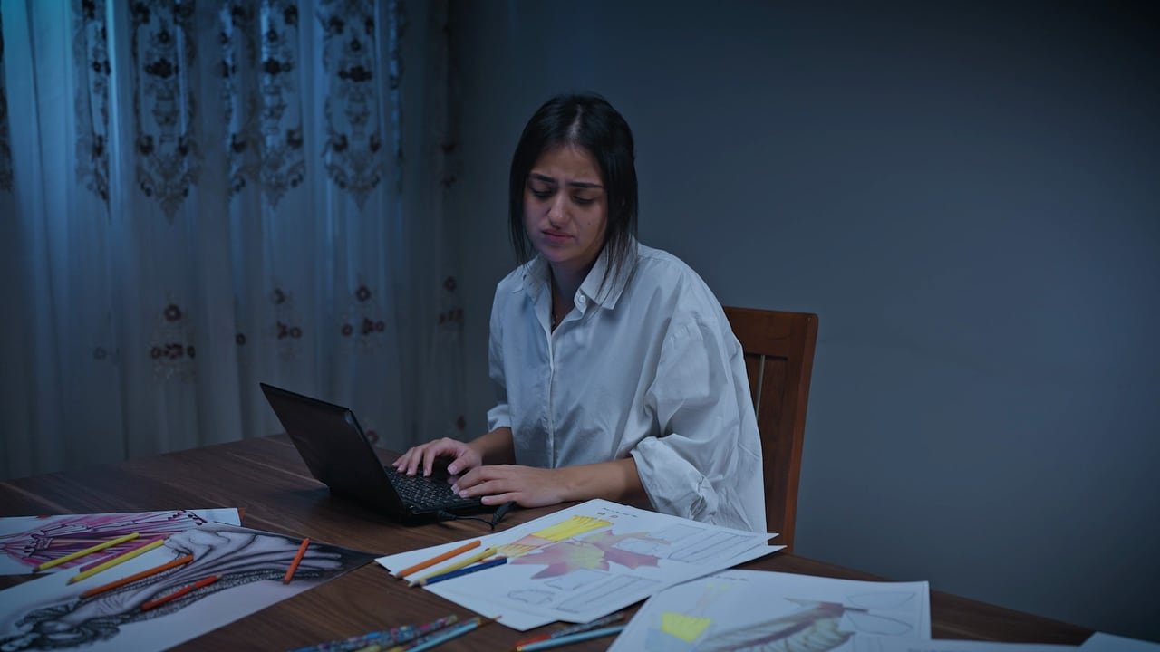 شابة تعمل على حاسوبها وسط رسوماتها.