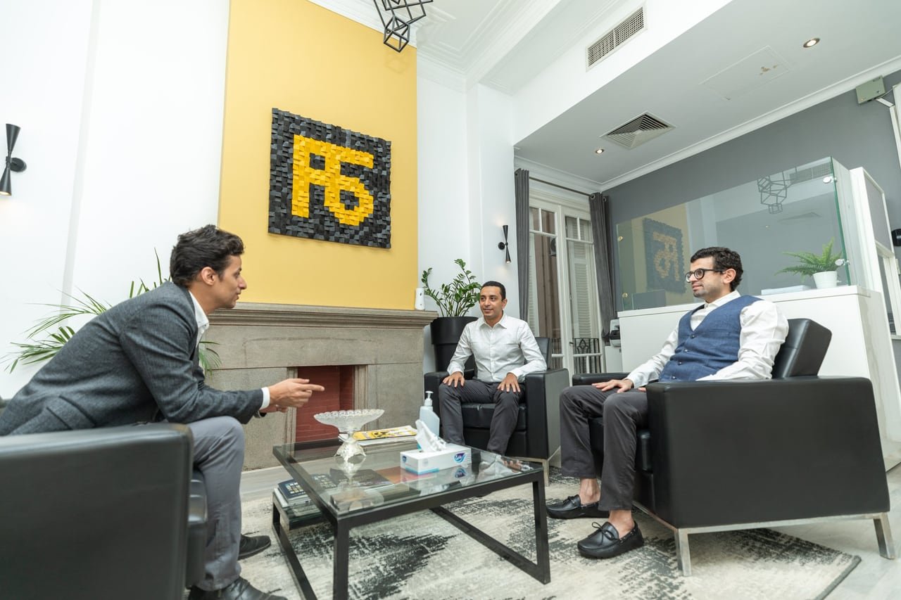 اجتماع في صالة Flat6Labs أمام جدار الشعار الأصفر.