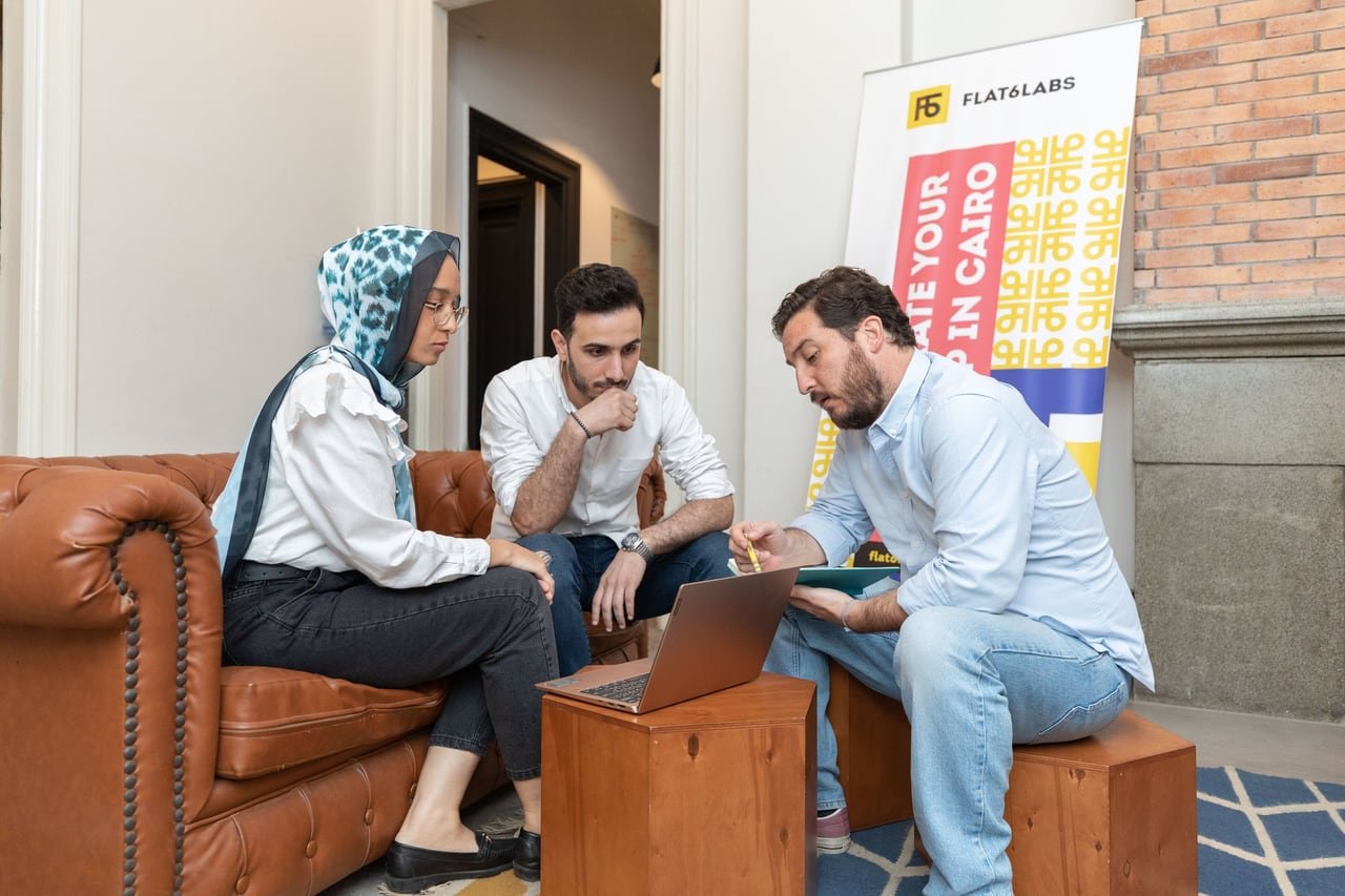 A meeting on a leather sofa beside a Flat6Labs banner.