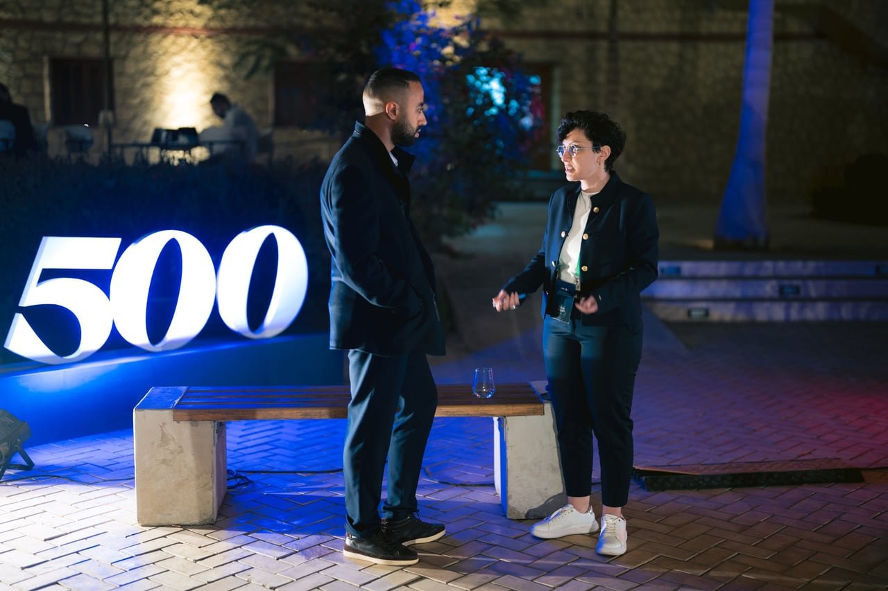 Two guests talking beside the lit 500 letters.
