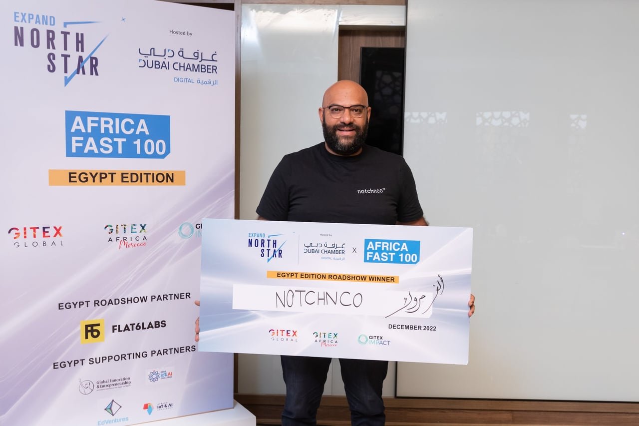 A winner holding the award board in front of the Africa FAST 100 banner.
