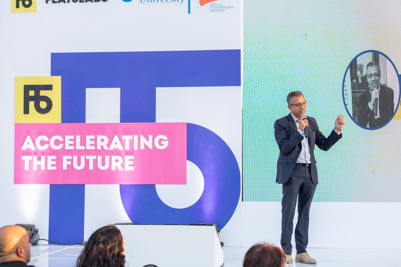 A speaker on stage in front of the Accelerating the Future backdrop.