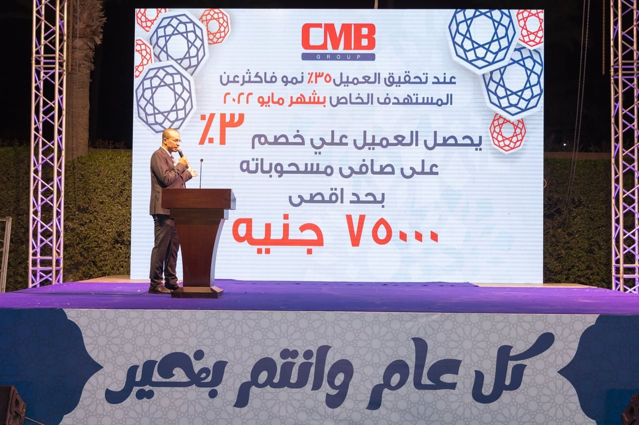 A speaker on stage in front of the CMB offers screen.
