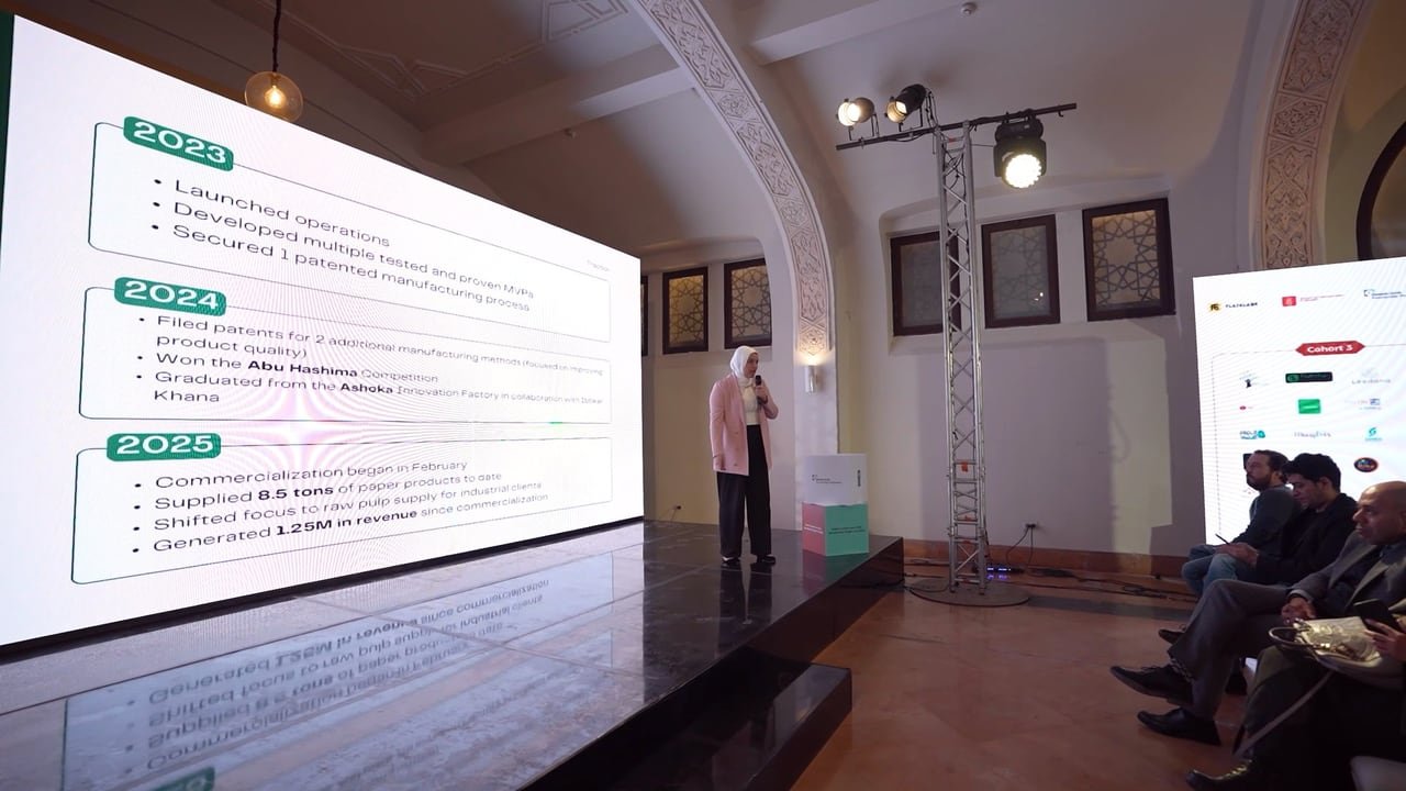 A presenter on stage in front of the programme timeline.