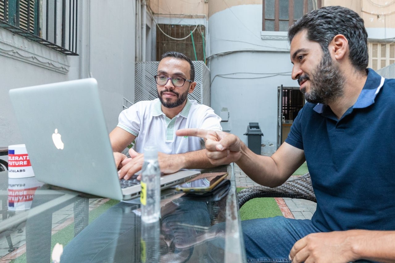 A team working on the terrace around a laptop.