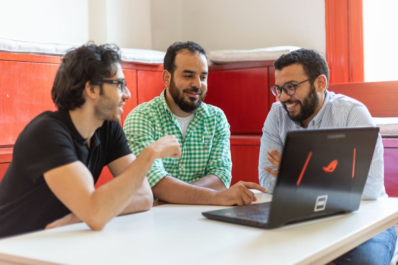 Three founders talking in the red room.