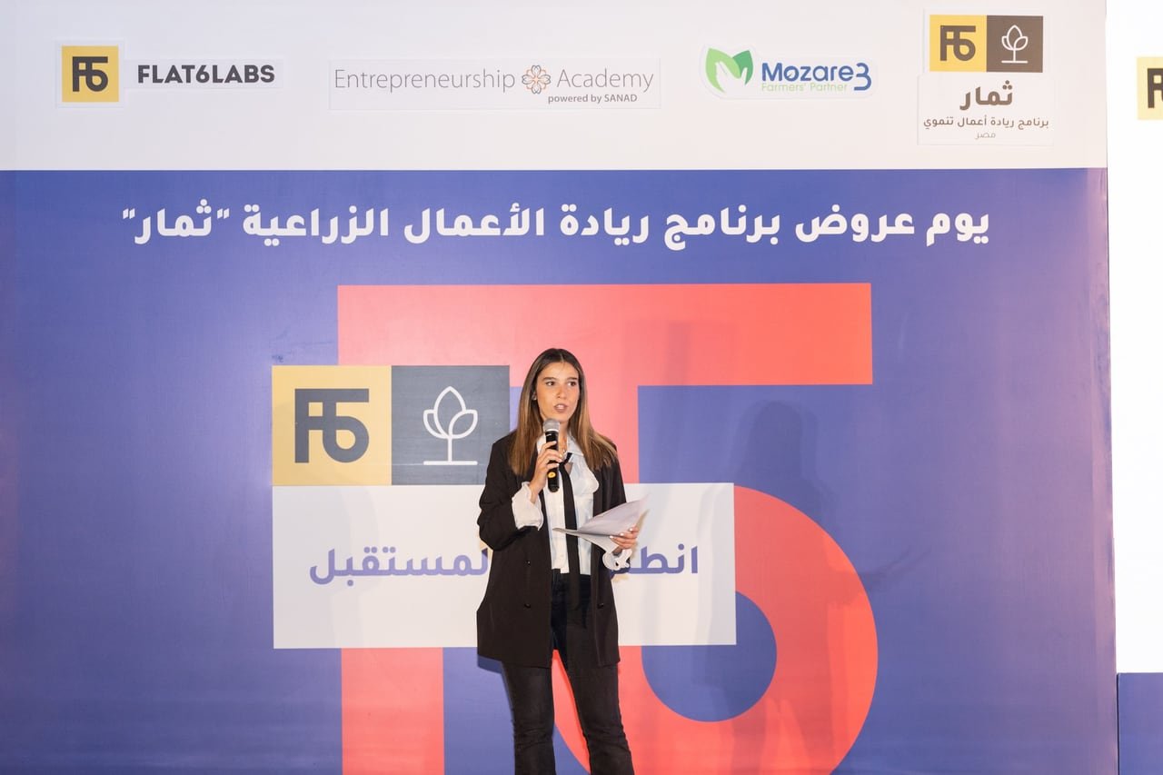 A founder presenting her project on the Thimar stage, microphone in hand.