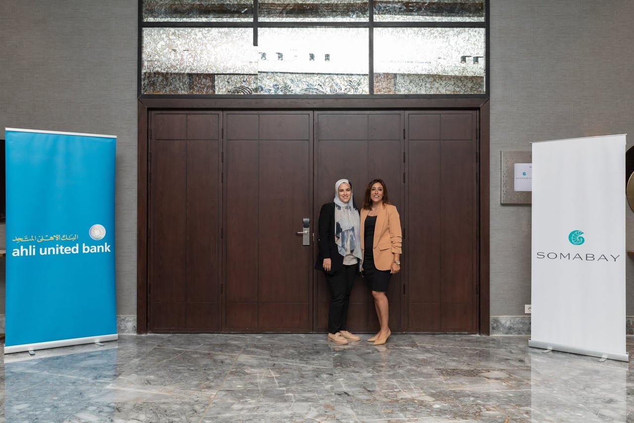 Two guests at the entrance between the bank and Somabay banners.