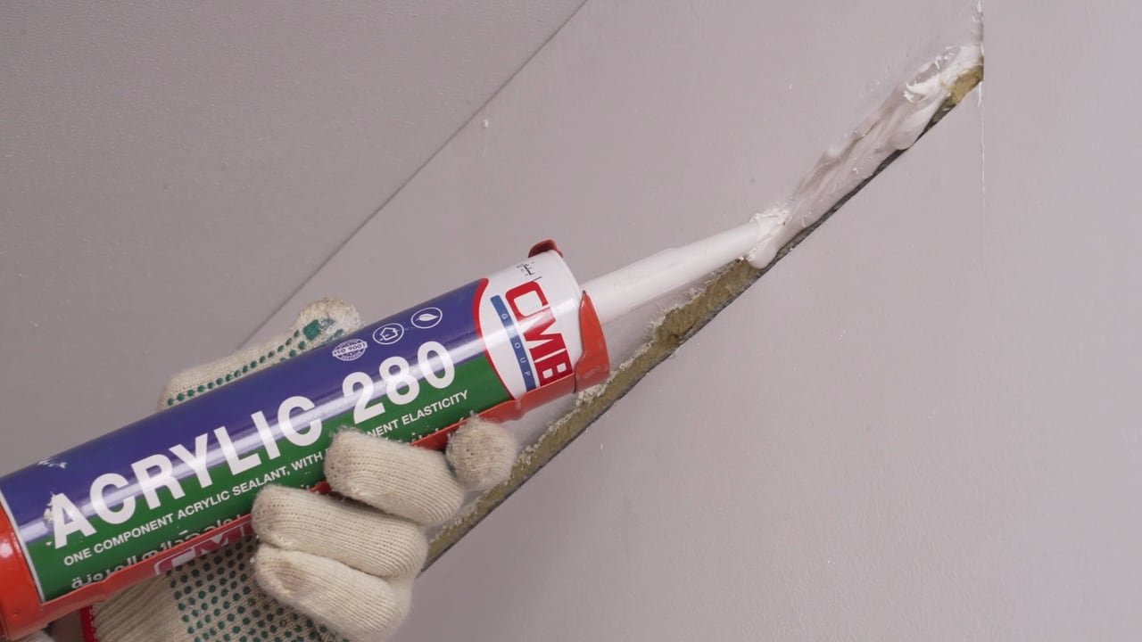 A gloved hand holding a tube of Acrylic 280 sealant.