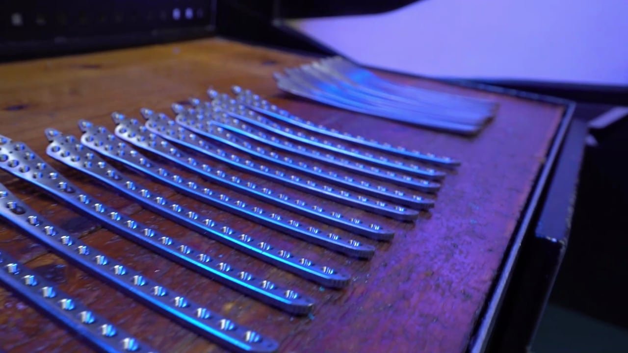 Orthopaedic plates laid out under blue light.